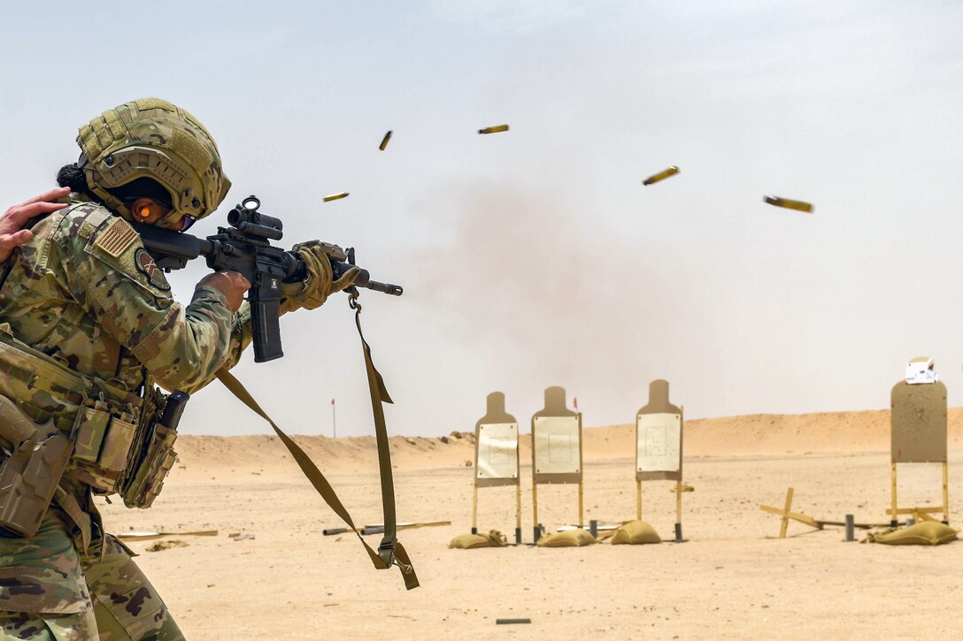An airman fires his weapon at a target.