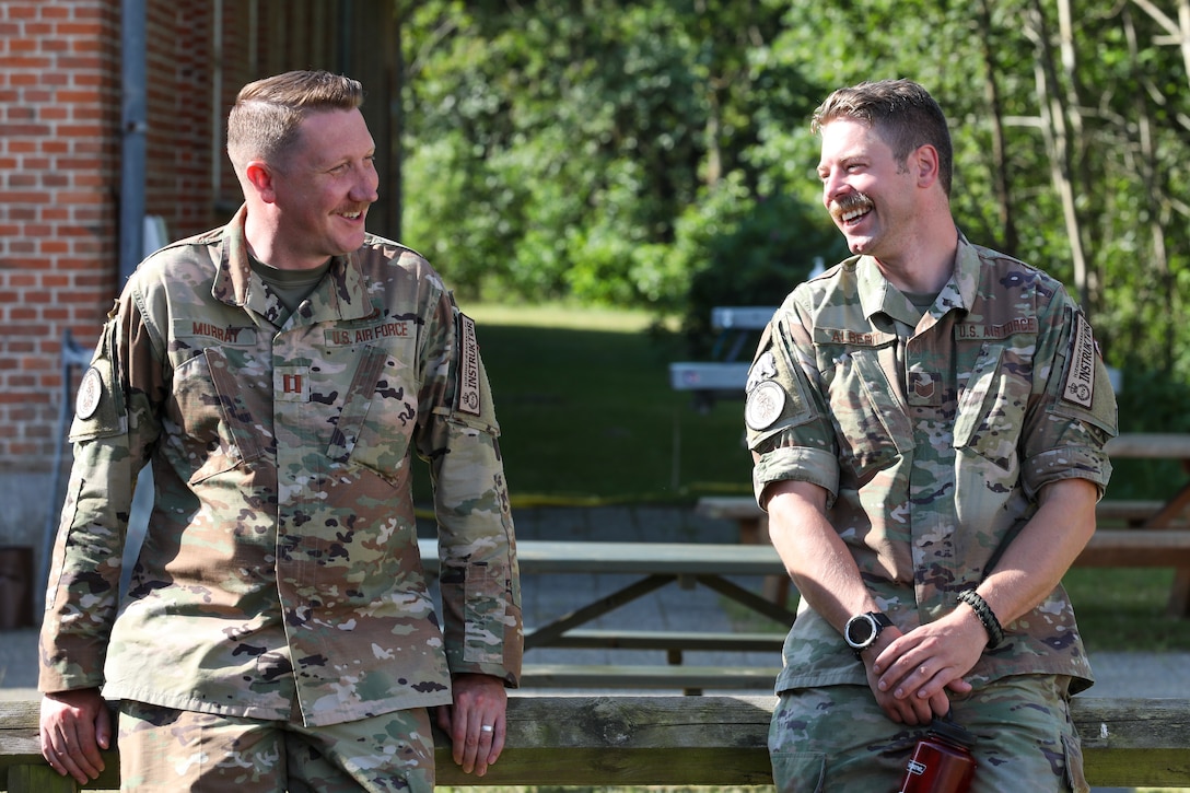 ANG Captain Matthew Murray enjoys the weather with Tech Sgt. Cody Albert after teaching the Basic Instructors Course at Camp Nymindegab July 3, 2022. MREP is a program that houses almost 130 participants from 6 different nations, to increase interoperability, strengthen partnerships, and to enhance professional development between allies.