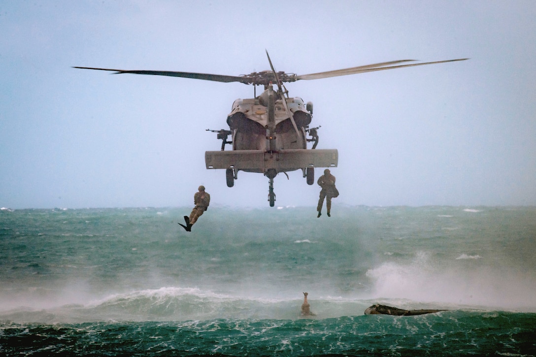 U.S. and South Korean troops jump into a body of water from an airborne helicopter.
