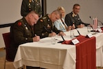 U.S. Army Brig. Gen. Gregory Knight, left, Vermont adjutant general, and U.S. Army Gen. Daniel Hokanson, center left, chief of the National Guard Bureau, sign letters of intent with the Republic of Austria in Vienna, Austria, July 19, 2022, under the State Partnership Program. This is the third state partnership for the Vermont National Guard, which has partnered with North Macedonia since 1993 and Senegal since 2008.