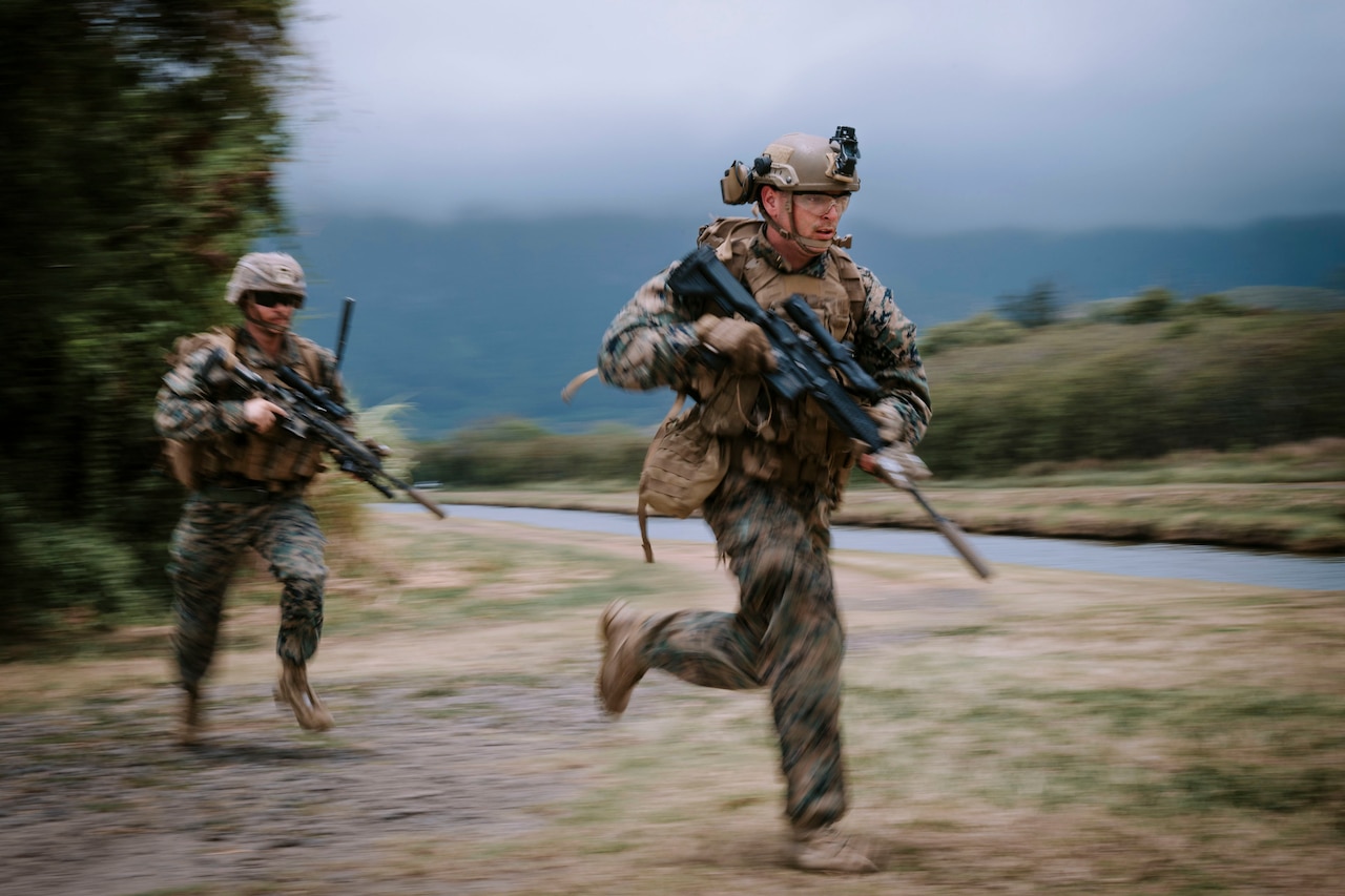 Two Marines run while holding weapons.