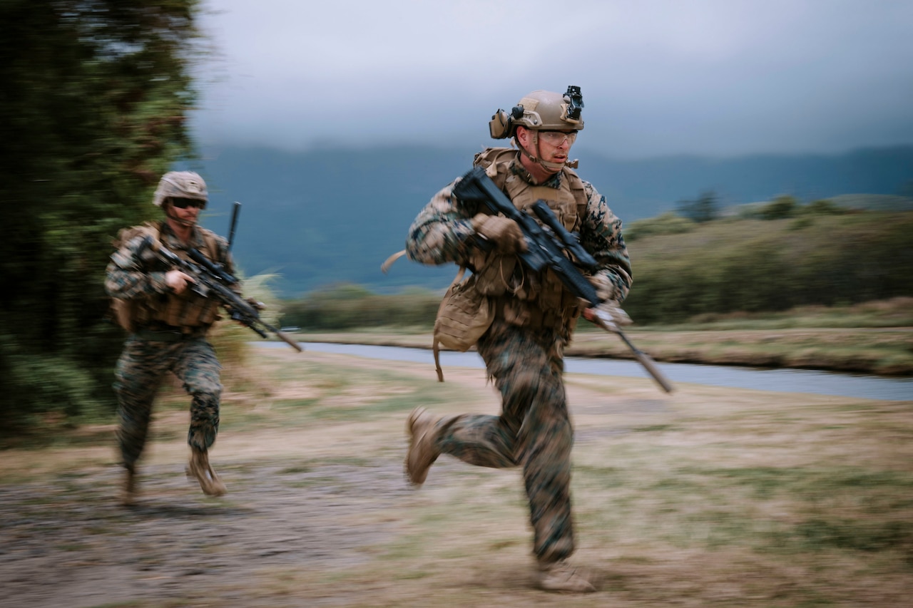 Two Marines run while holding weapons.