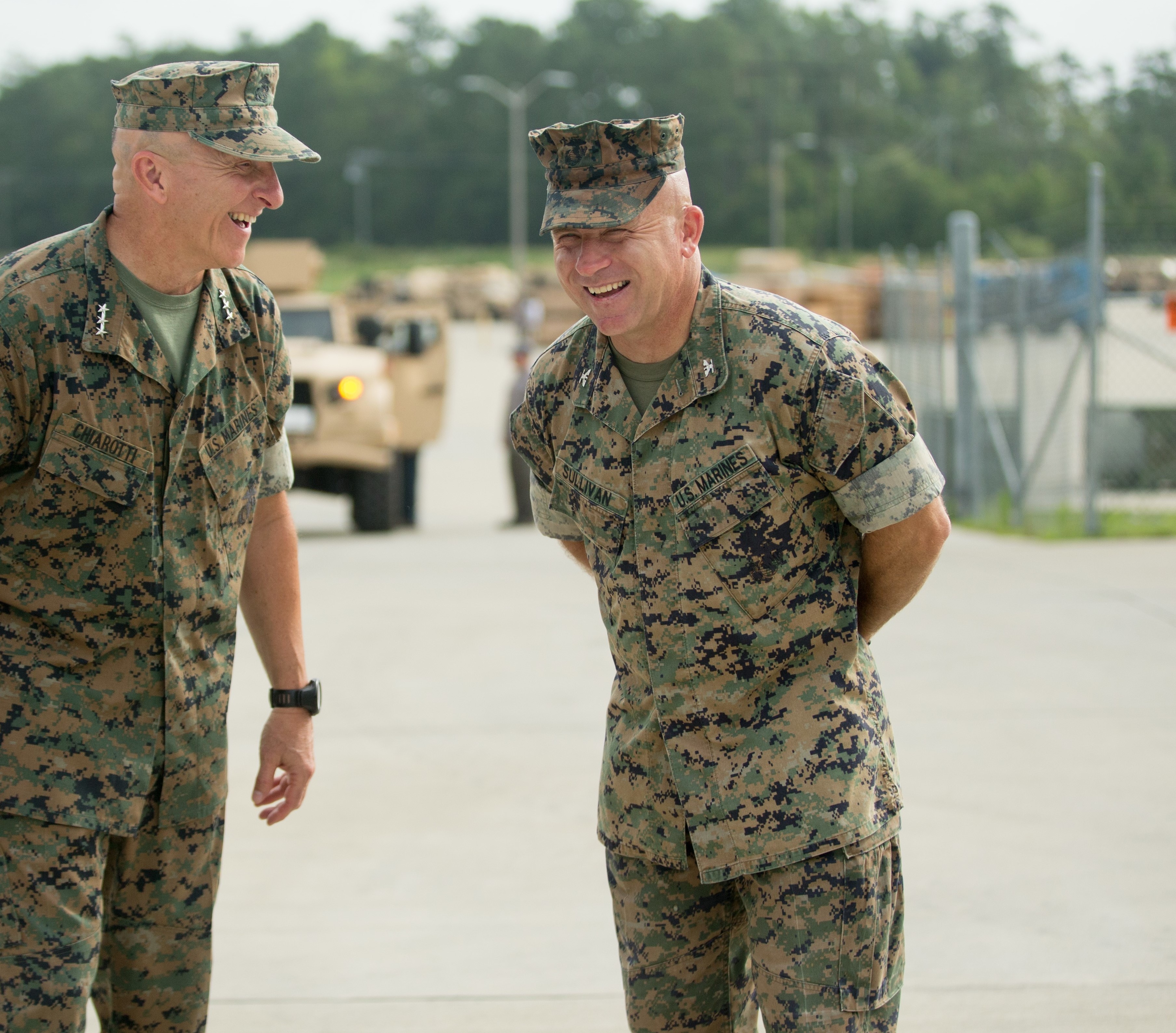Two Marines in uniform laughing together.