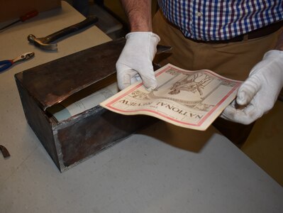 Courtney Burns, director of the New York State Military Museum, examines an issue of the African-American publication, “The National Review,” found in a time capsule box discovered during renovation of the original section of the New York National Guard’s historic Harlem Armory. The box contained documents pertaining to the 369th “Harlem Hellfighters” of World War I fame and documents of importance to the Black community in 1923 New York City.