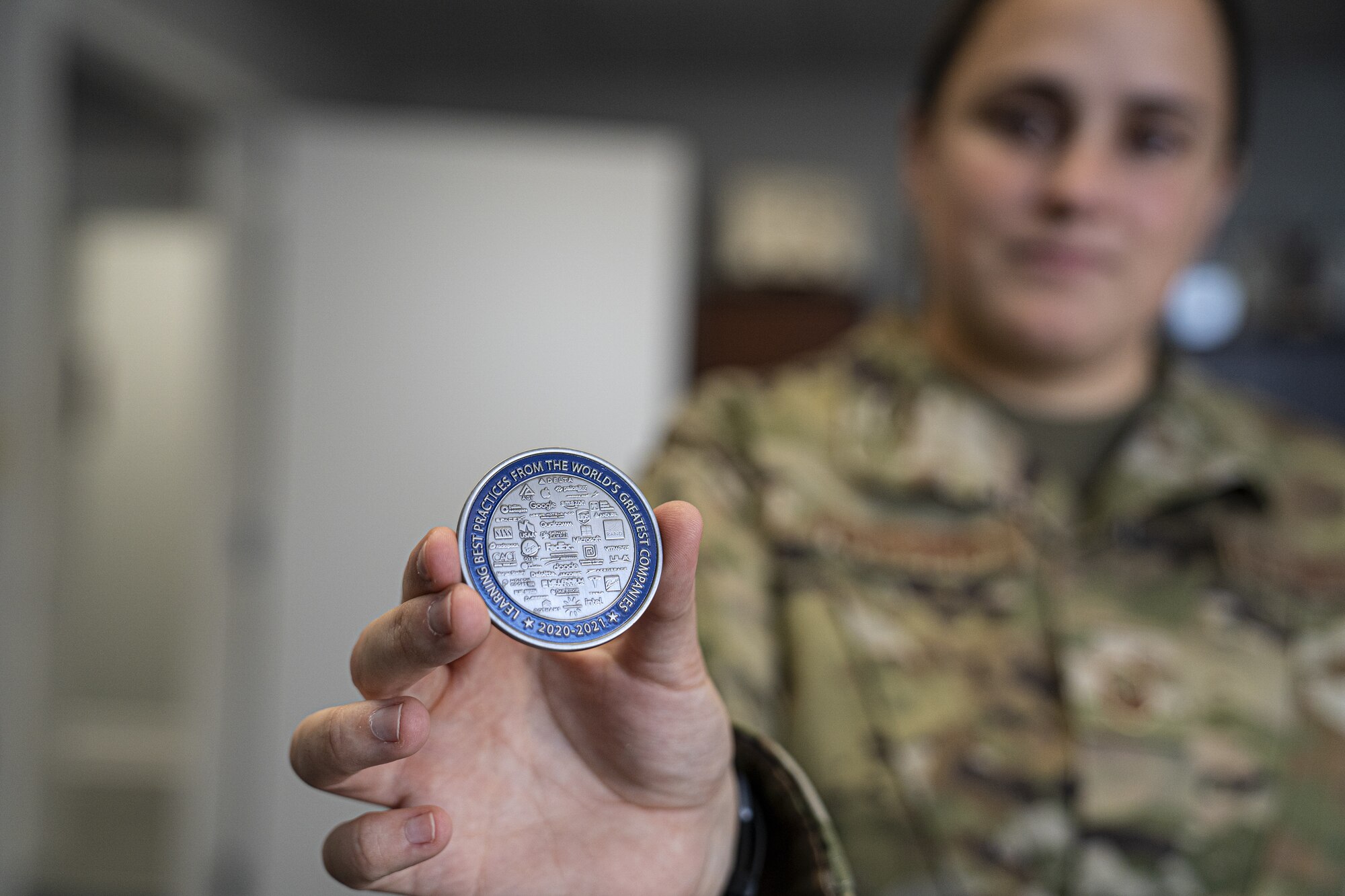 U.S. Air Force Master Sgt. Alexandria Verissimo, 81st Training Wing executive support services superintendent, presents an Education With Industry coin at Keesler Air Force Base, Mississippi, July 26, 2022. Education With Industry is a program that allows service members and civilians to be imbedded into companies to learn professional competencies. (U.S Air Force photo by Airman 1st Class Trenten Walters)
