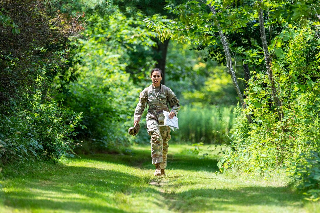 A soldier runs on a trail on grass.