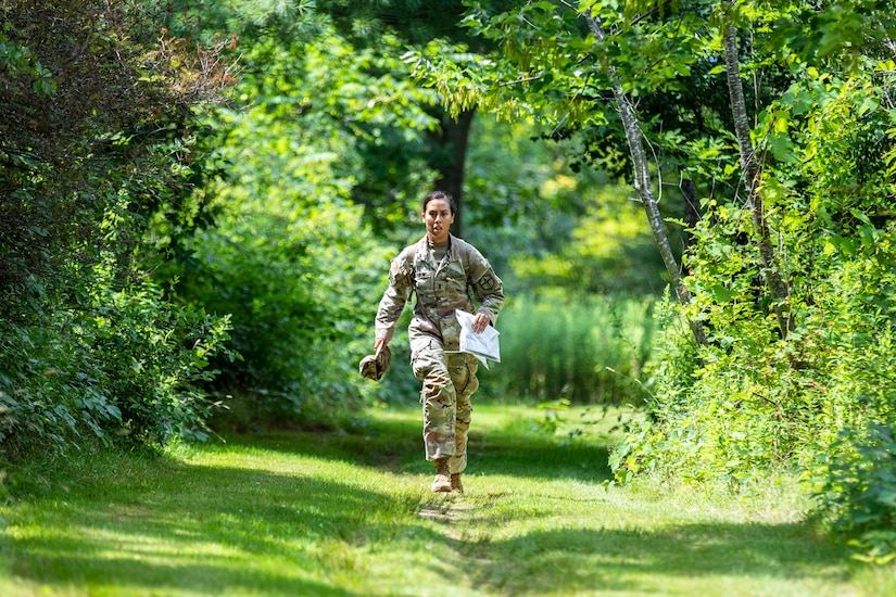 A soldier runs on a trail on grass.