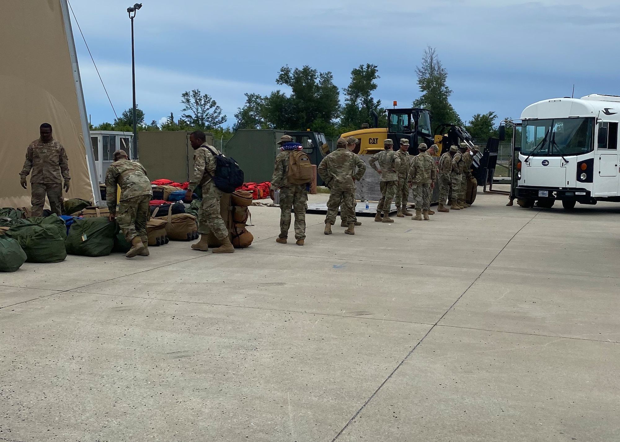 U.S. Airmen drop off deployment gear prior to loading a bus at the 325th Logistics Readiness Squadron Installation Deployment Readiness Center staging area before loading onto a bus at Tyndall Air Force Base, Florida, July 6, 2022. Members must process through the IDRC as their final step before departing for their deployments. (Courtesy Photo)