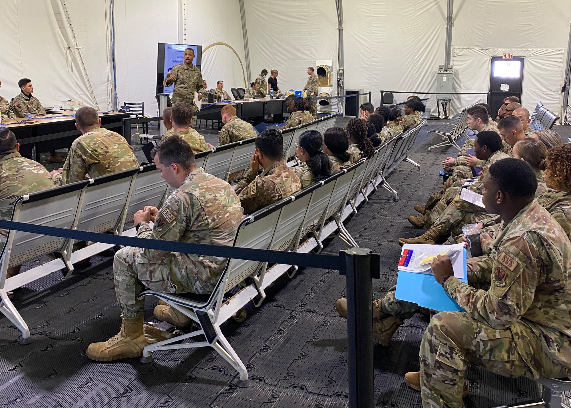 U.S. Airmen receive a predeployment briefing at the 325th Logistics Readiness Squadron Installation Deployment Readiness Center staging area at Tyndall Air Force Base, Florida, July 6, 2022. Members are briefed from various Tyndall agencies such as the Airman and Family Readiness Center, Legal office, Chaplain corps and Military Personnel Flight before they transition overseas. (Courtesy Photo)