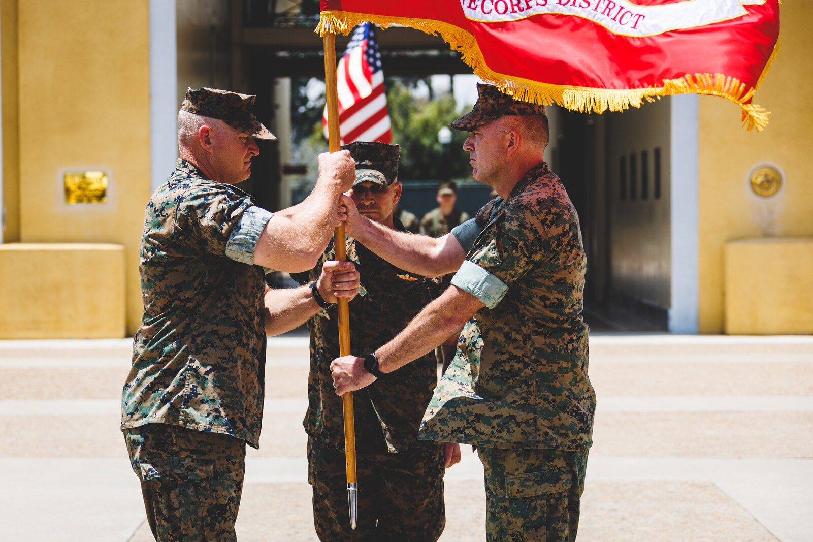 U.S. Marine Corps Col. James B. Conway (right), the outgoing commanding officer, passes the organizational colors to Col. Mike E. Ogden (left), the oncoming commanding officer, during a change of command and retirement ceremony at Marine Corps Recruit Depot San Diego, California, July 15, 2022.
