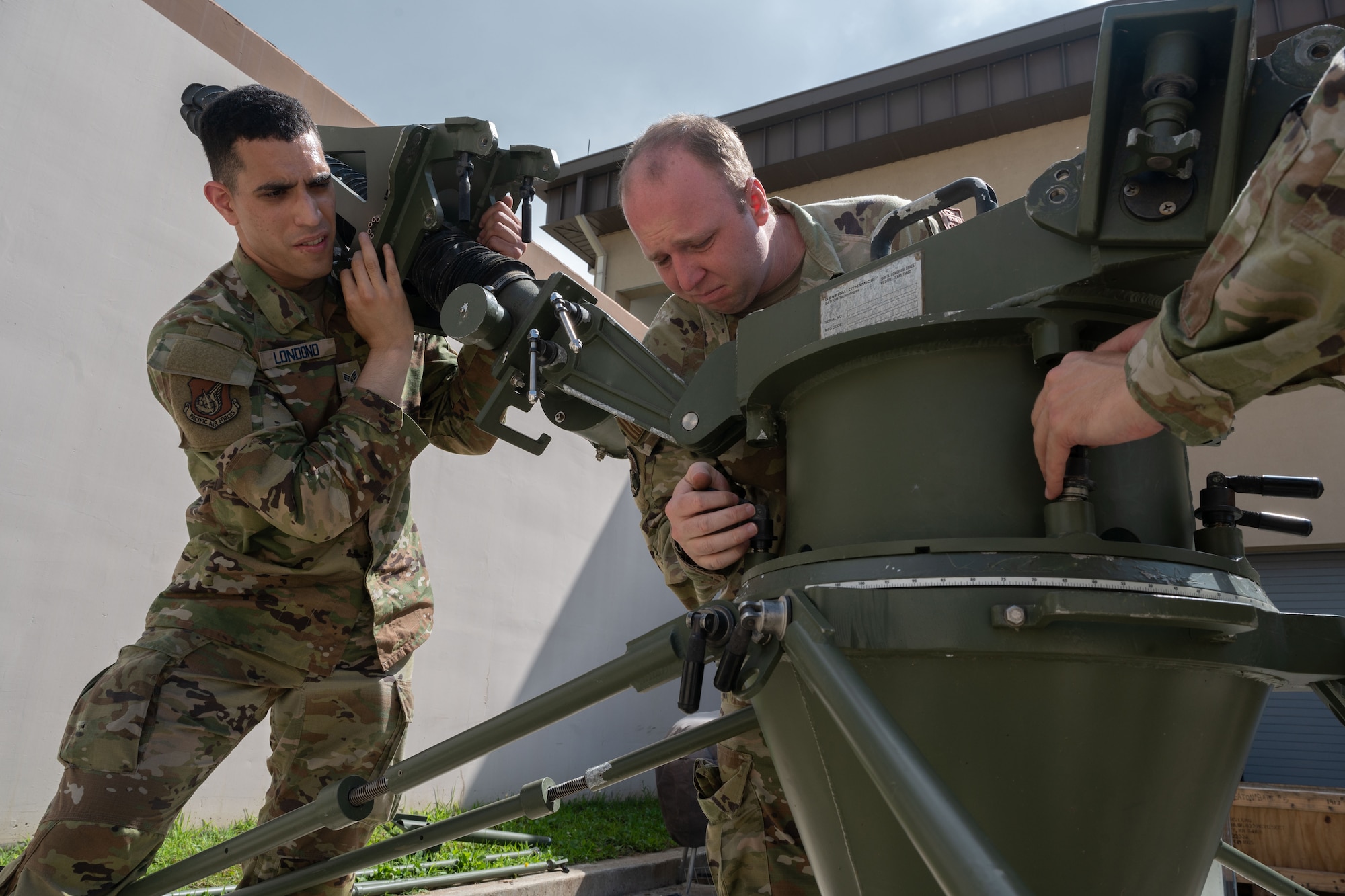 Military members disassemble a satellite