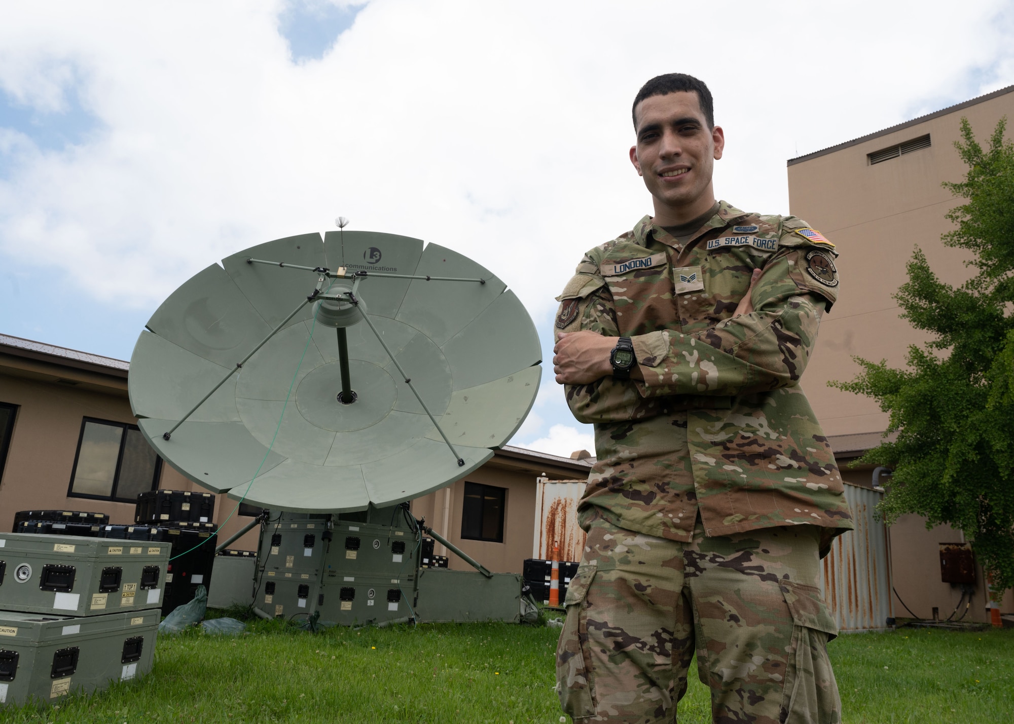 A military member poses by a satellite