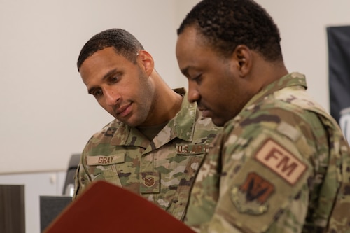 U.S. Air Force Tech. Sgt. Amos Gray, 325th Comptroller Squadron financial operations supervisor, receives a deployment briefing from Tech. Sgt. Micah Mincey, 325th CPTS unit deployment manager, at Tyndall Air Force Base, Florida, July 15, 2022. UDMs act as liaisons between various Air Force units and the individual service members tasked to deploy. (U.S. Air Force photo by Staff Sgt. Cheyenne Lewis)