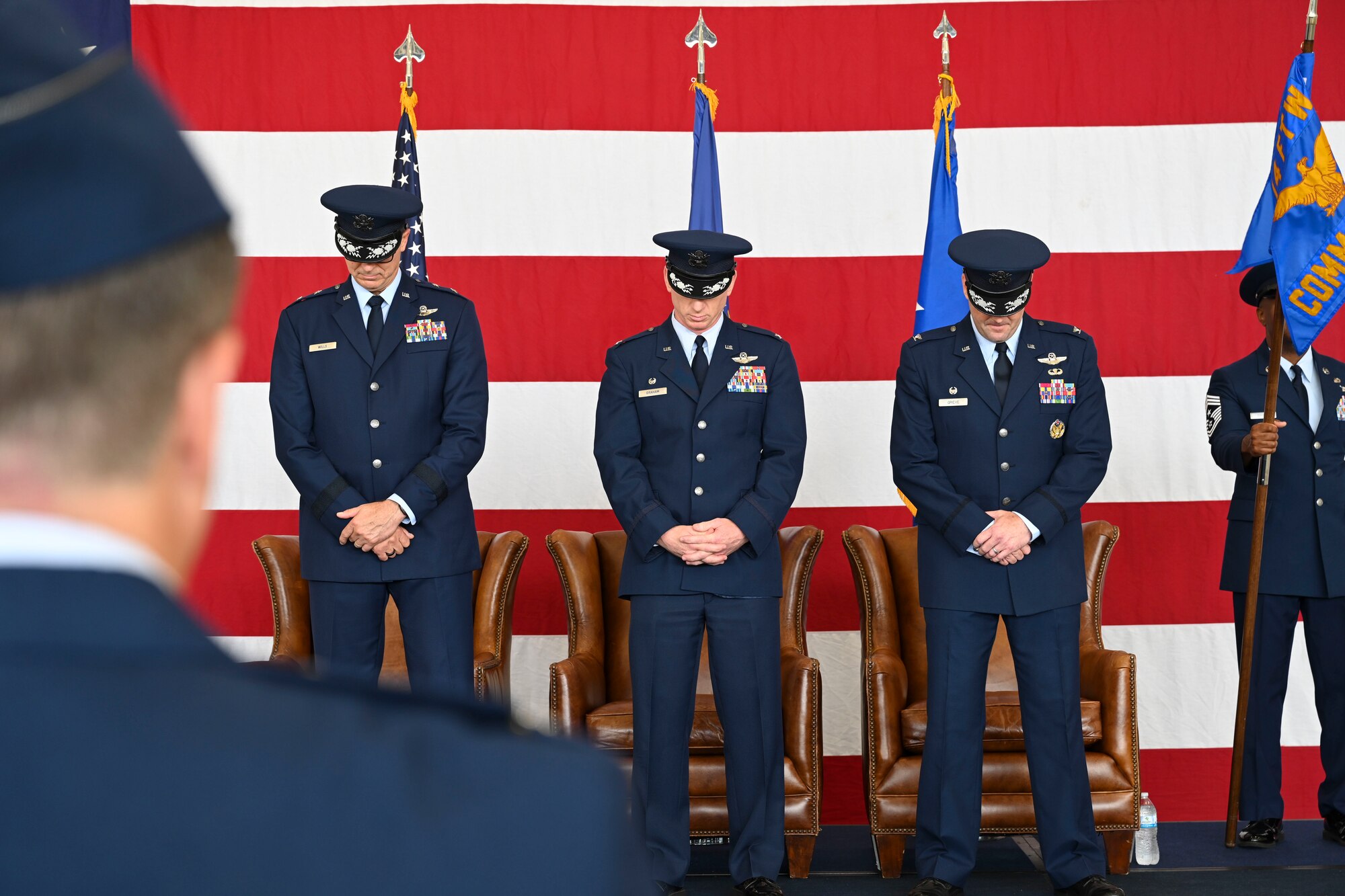 U.S. Air Force Maj. Gen. Craig Wills, 19th Air Force commander (left),  Col. Seth Graham, outgoing 14th Flying Training Wing commander, Col. Justin Grieves, incoming 14 FTW commander (right), stand as the innvocation is delivered at the 14th FTW Change of Command ceremony on Columbus Air Force Base, Miss., July 22, 2022. The 19th Air Force is composed of more than 36,000 total force personnel and 1,608 aircraft assigned to 17 Total Force wings located across the U.S. ( U.S. Air Force Senior Airman Jessica Haynie)