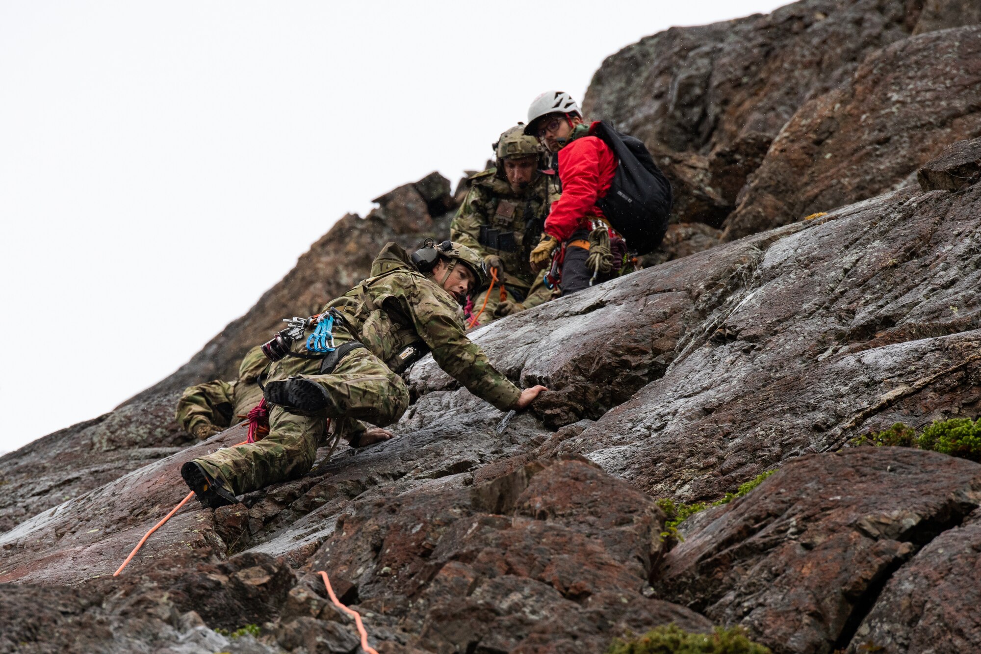 An Airman climbs a steep cliff.