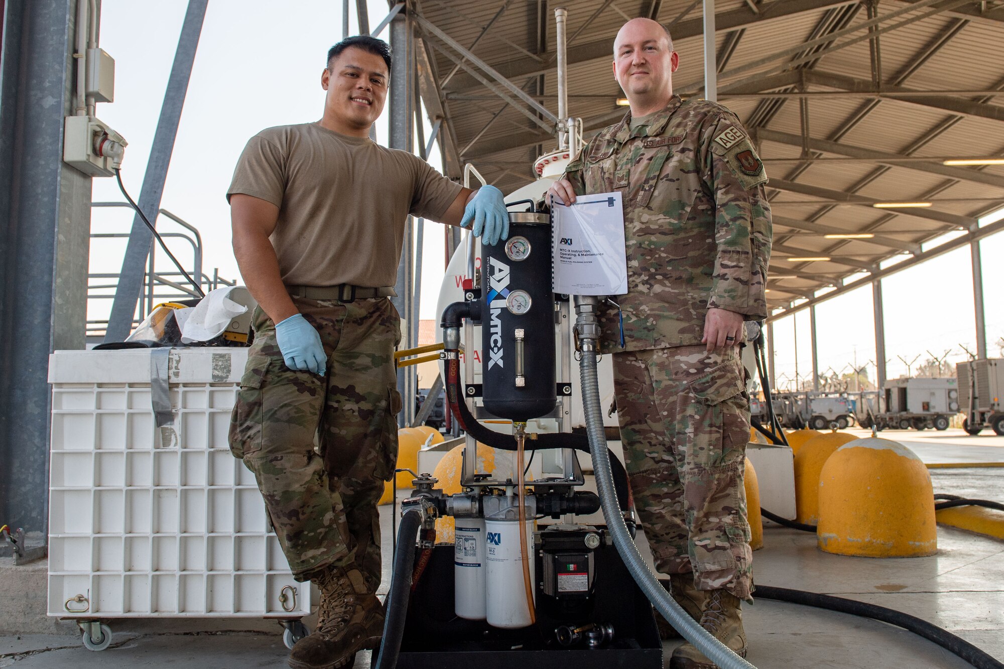 U.S. Air Force Tech. Sgt. Thai MacLeod, 31st Maintenance Squadron aerospace ground equipment (AGE) section chief, right, and Senior Airman Shane Villegas, 31st MXS AGE journeyman, left, pose for a photo with the AGE fuel polisher