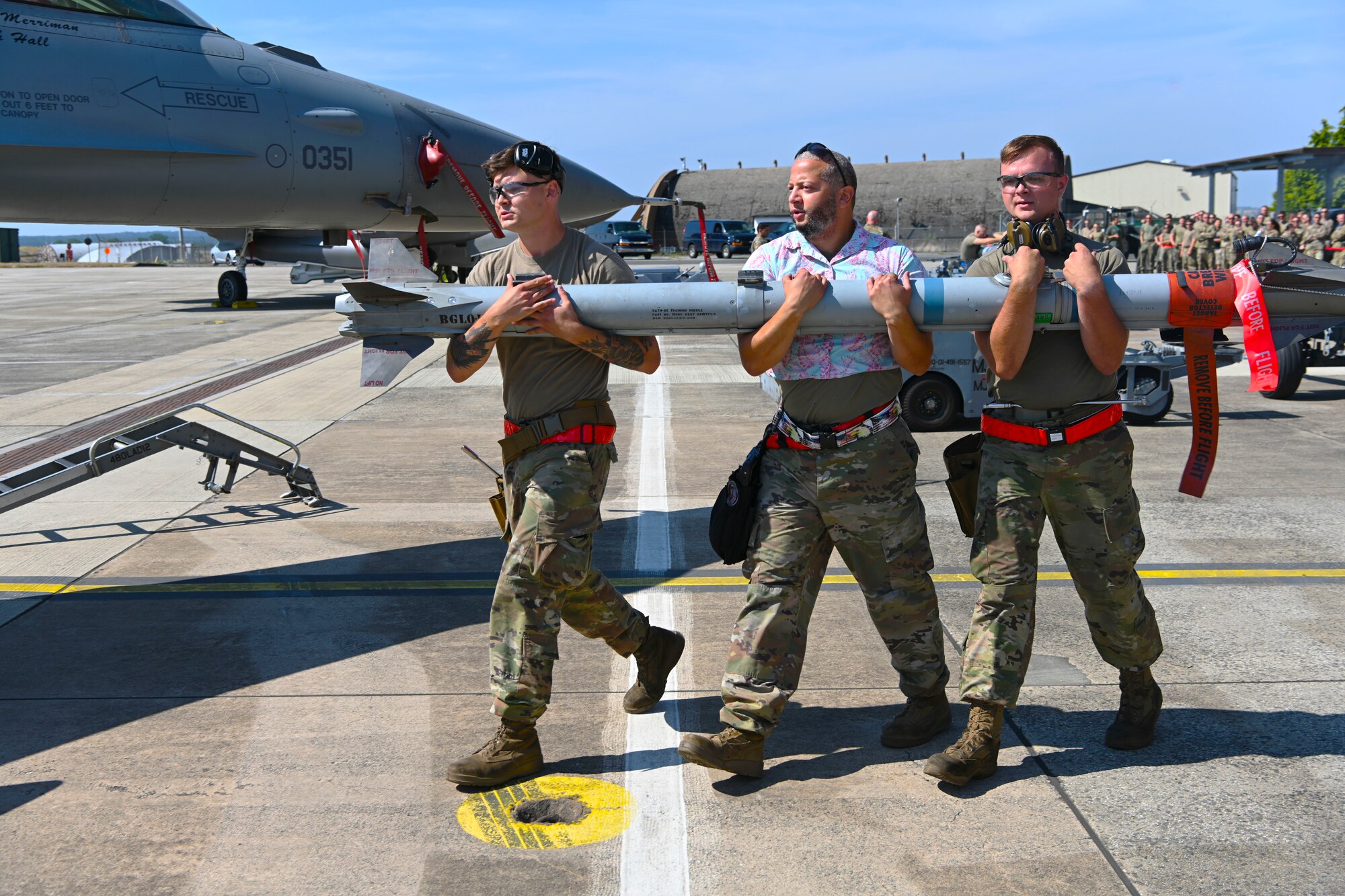 Three Airmen carrying a missile