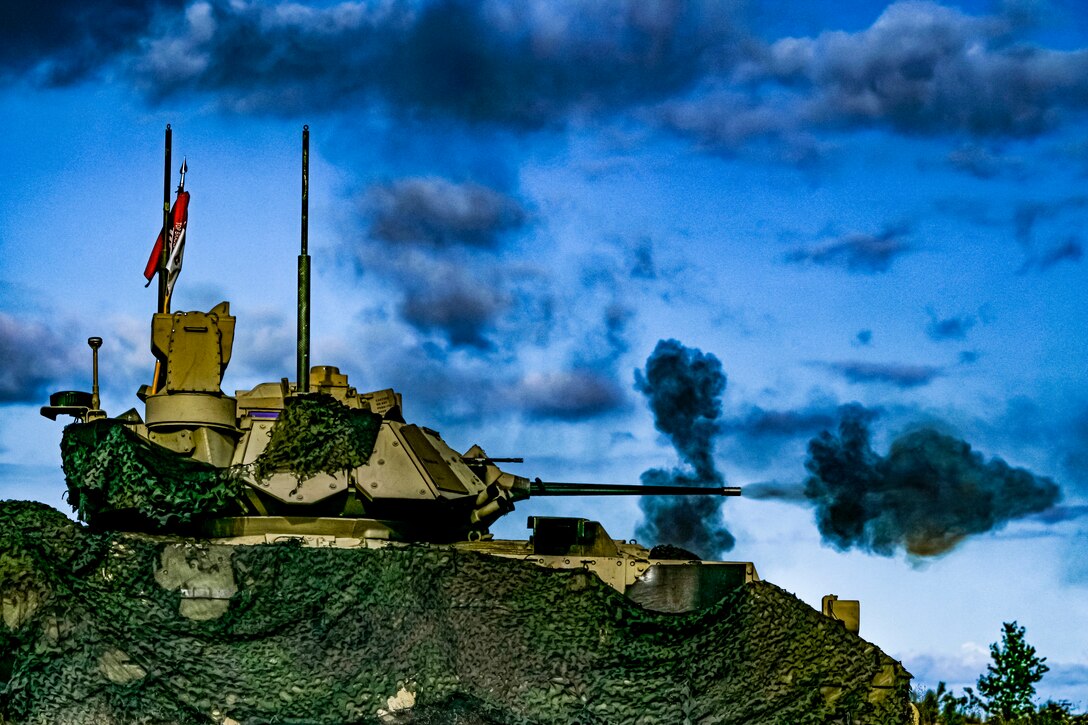 Dark smoke shoots out from a weapon on a tank.