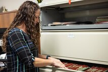 Woman sorts through files in filing cabinet.