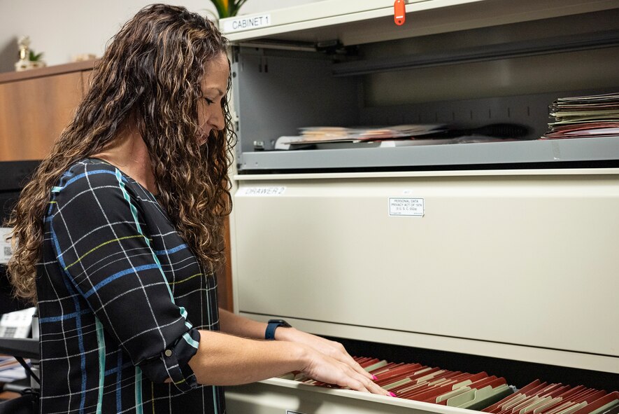 Woman sorts through files in filing cabinet.