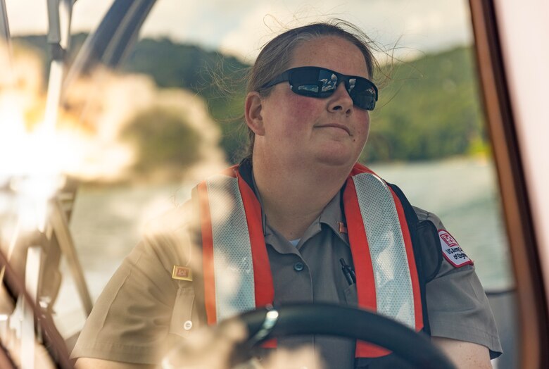 Karen Osler, park ranger, driving a boat with sun and clouds reflecting off the windshield