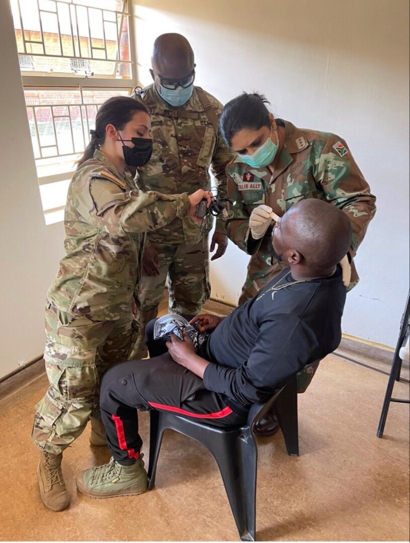 New York Army National Guard Staff Sgt. Christine Iraci, left, and Army Reserve Maj. Dwayne Bodie look on as Anissa Talib-Ally of the South African Military Health Service checks a patient outside Richards Bay, South Africa, during a medical readiness visit July 25, 2022, as part of Exercise Shared Accord.