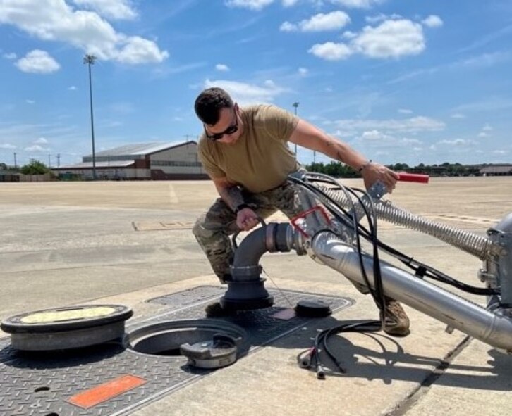 An Airman connects a “pantograph” hot-pit re-fueling vessel to an underground pipeline.