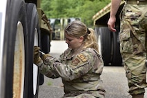 An Airman checks the tire pressure on a tractor trailer.
