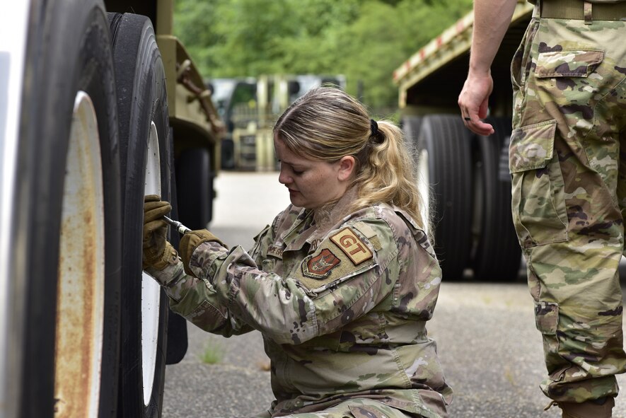 An Airman checks the tire pressure on a tractor trailer.