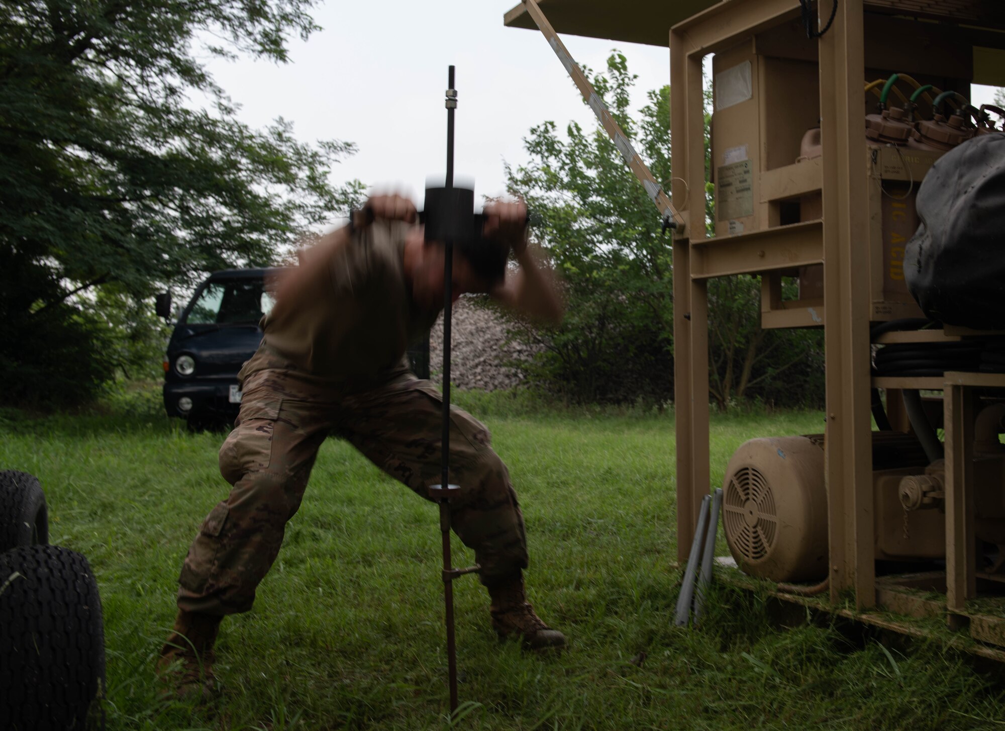 An Airman drives a stake into the ground to dig a hole.