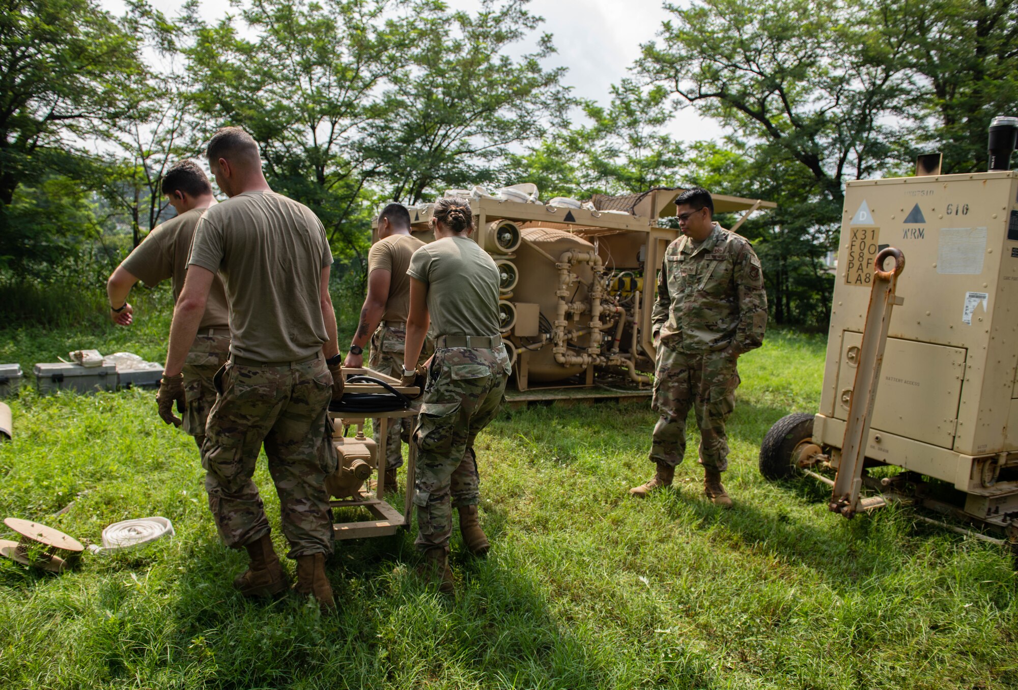Airmen carry a machine used to purify water.