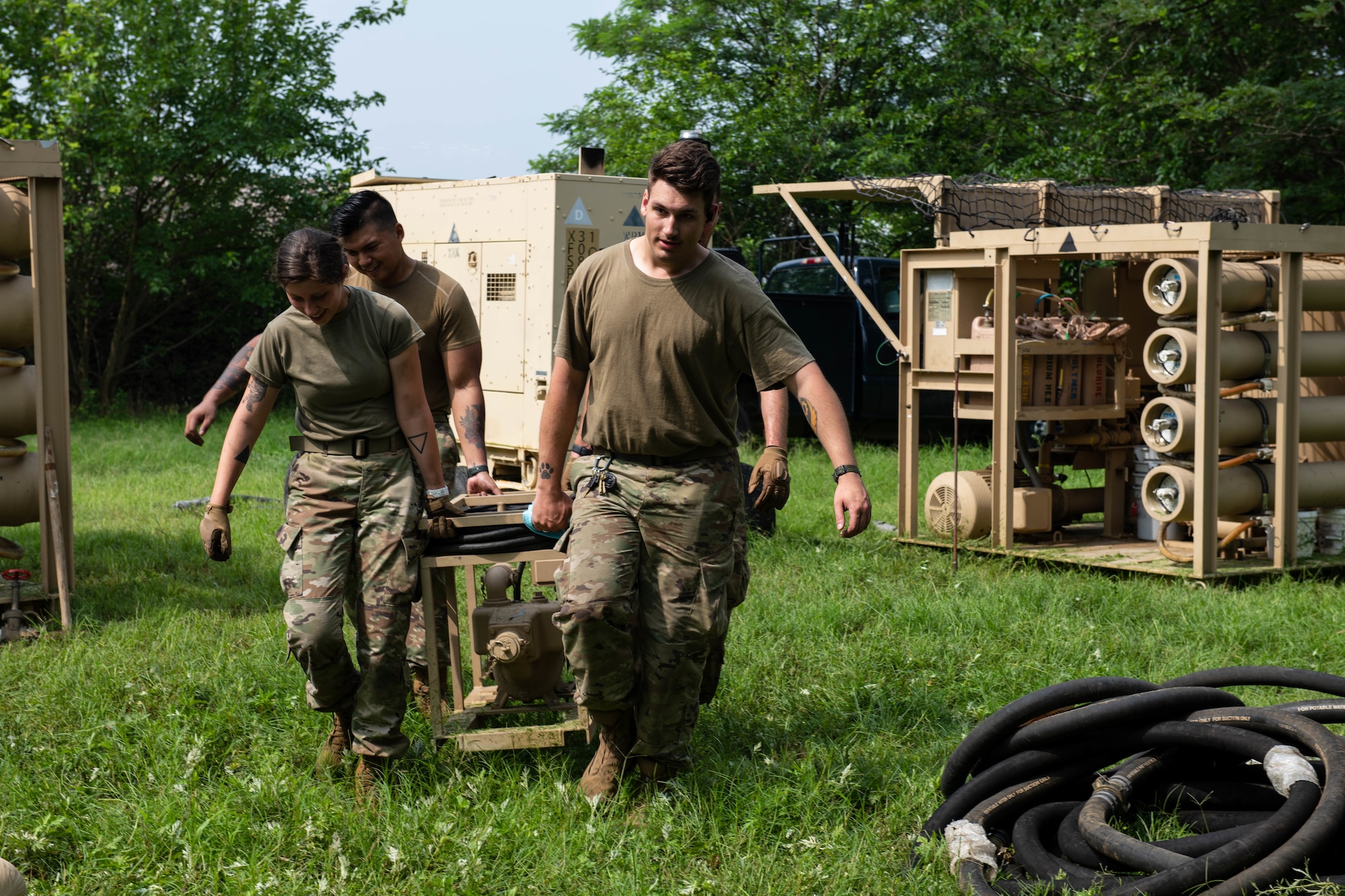 Airmen carry a machine used to purify water