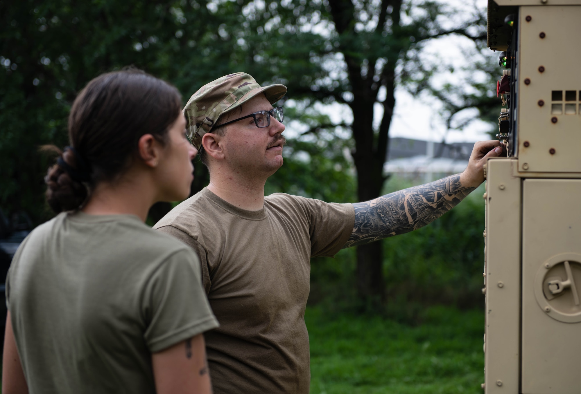 Two Airmen talk beside a piece of equipment.