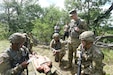 U.S. Army Reserve Sgt. Baylee Jones, standing, Observer Coach Trainer, observes how Spc. Jalen Middleton, bottom left, truck driver for the 630th Transportation Company, gives a Nine-Line Medical Evacuation during medical lane training at Warrior Exercise 78 at Fort McCoy, Wisconsin, July 19, 2022.