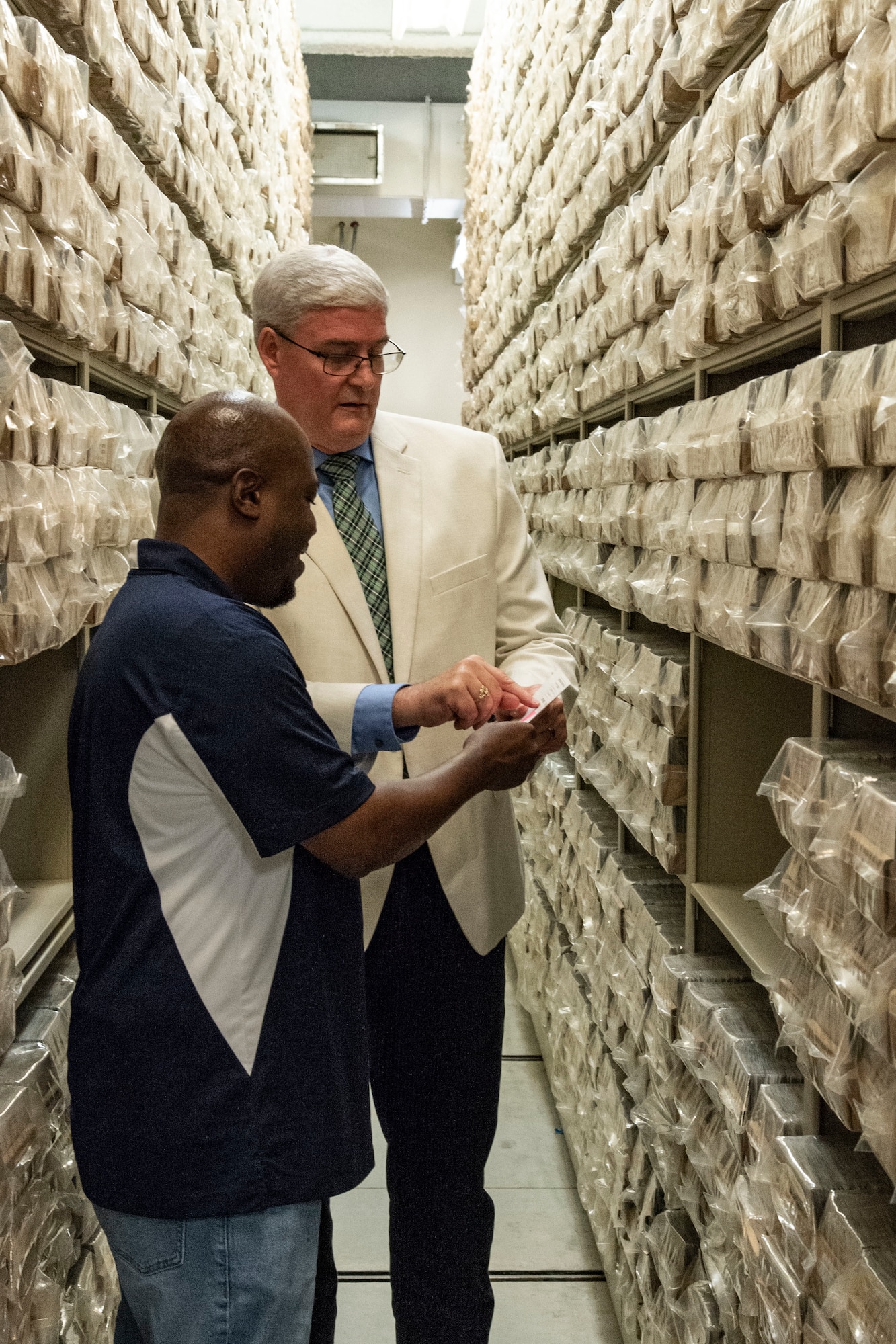 Dr. Timothy McMahon, right, Armed Forces Medical Examiner System Department of Defense DNA Operations director, shows Jeffrey Benson, left, 3rd Airlift Squadron honorary commander, the location of his DNA reference card in the DNA reference card repository at Dover Air Force Base, Delaware, July 22, 2022. Since 1992, DNA reference cards containing a blood sample of U.S. service members have been collected and stored in the repository. (U.S. Air Force photo by Roland Balik)