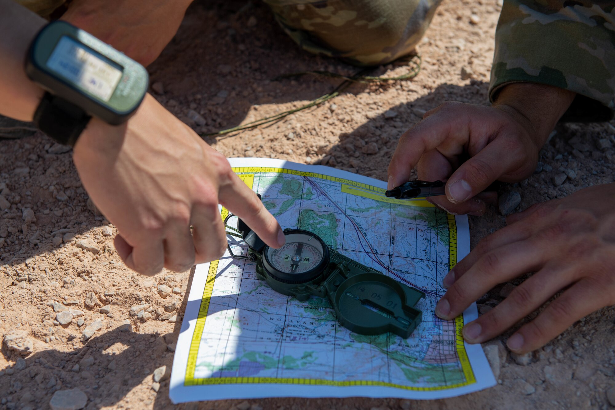 U.S. Air Force Staff Sgt. Jerrel Ponce and Airman 1st Class Rahkem Harris, 28th Operations Support Squadron intelligence analysts, determine their location on a map at the Fort Meade Training Area, S.D., July 21, 2022.