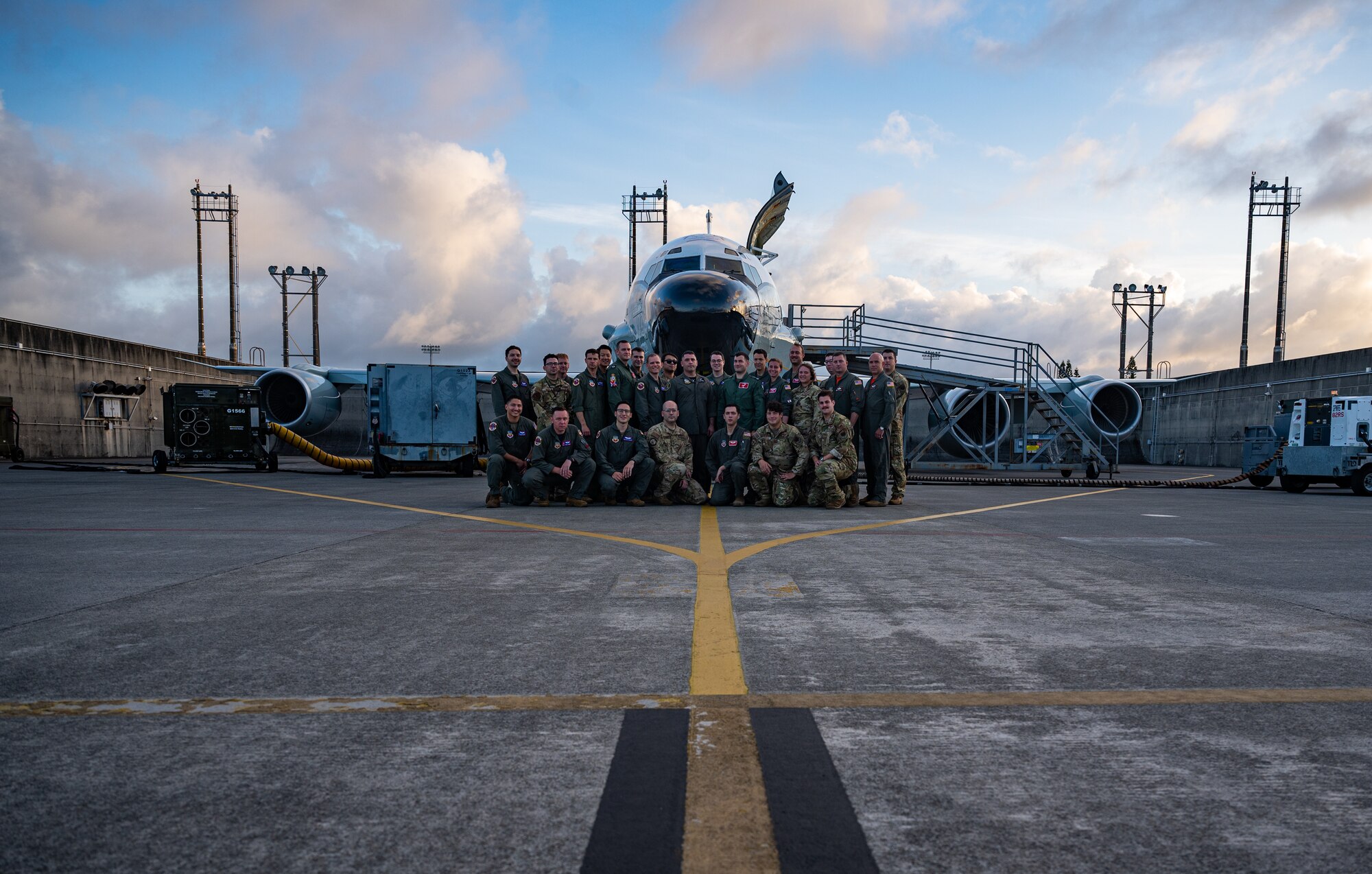 Service members pose in front of an aircraft.