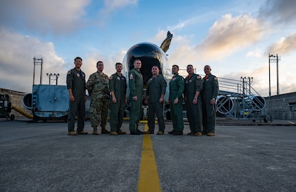 Service members pose in front of an aircraft.