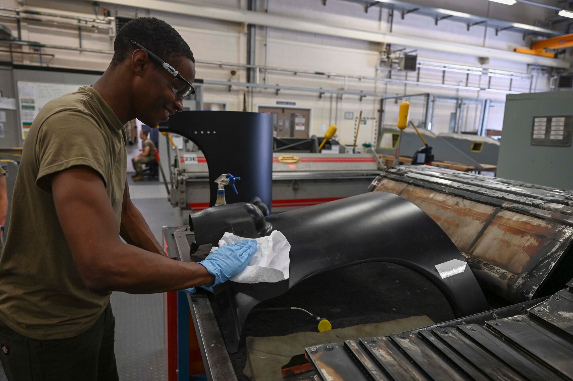 U.S. Air Force Airman 1st Class Carl Jones, 100th Maintenance Squadron sheet metal journeyman, polishes a CV-22 Osprey aircraft body panel at Royal Air Force Mildenhall, England, July 19, 2022. Constant upkeep of the CV-22 prolongs the life of the aircraft, and ensures they are ready to deploy rapidly and respond to critical situations globally. (U.S. Air Force photo by Airman 1st Class Viviam Chiu)