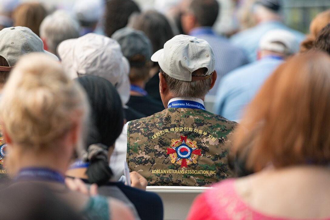 On July 27, 2022, a Marine Band trumpeter rendered "Taps" during a wreath laying ceremony for the dedication of the Korean War Veterans Memorial Wall of Remembrance. An audience member at the even wears a Korean Veterans Association vest. (U.S. Marine Corps photo by Staff Sgt. Chase Baran/released)