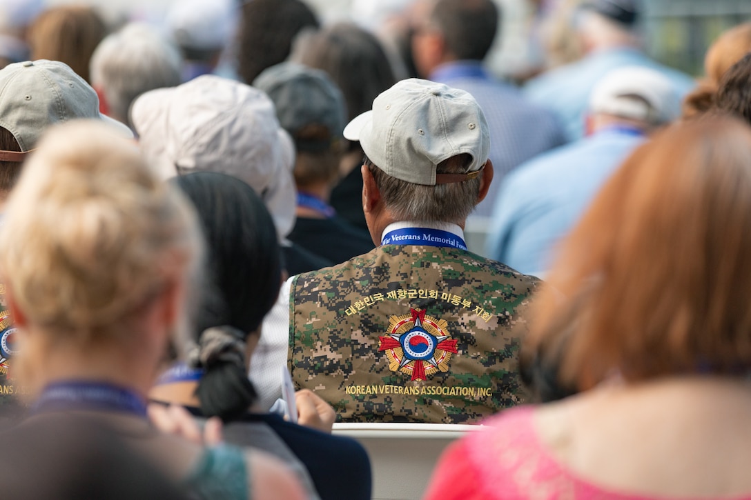 On July 27, 2022, a Marine Band trumpeter rendered "Taps" during a wreath laying ceremony for the dedication of the Korean War Veterans Memorial Wall of Remembrance. An audience member at the even wears a Korean Veterans Association vest. (U.S. Marine Corps photo by Staff Sgt. Chase Baran/released)