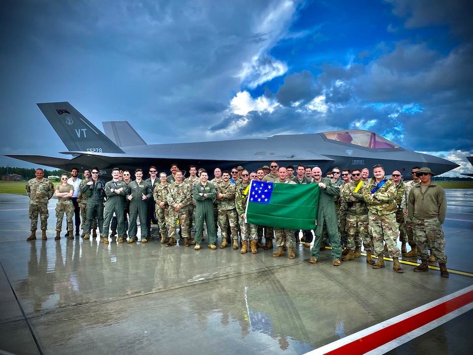 Airmen assigned to the Vermont Air National Guard’s 158th Fighter Wing hold a Green Mountain Battle flag in front of their U.S. Air Force F-35A Lighting II after successfully completing an Agile Combat Employment exercise to support the NATO Air Shielding mission at Amari Air Base, Estonia, July 15, 2022. Exercises and engagements in the European area of responsibility demonstrate U.S. commitment to the security and stability in this region. (U.S. Air Force courtesy photo)