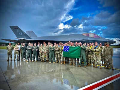 Airmen assigned to the Vermont Air National Guard’s 158th Fighter Wing hold a Green Mountain Battle flag in front of their U.S. Air Force F-35A Lighting II after successfully completing an Agile Combat Employment exercise to support the NATO air shielding mission at Amari Air Base, Estonia, July 15, 2022. Exercises and engagements in the European area of responsibility demonstrate U.S. commitment to the security and stability in this region.