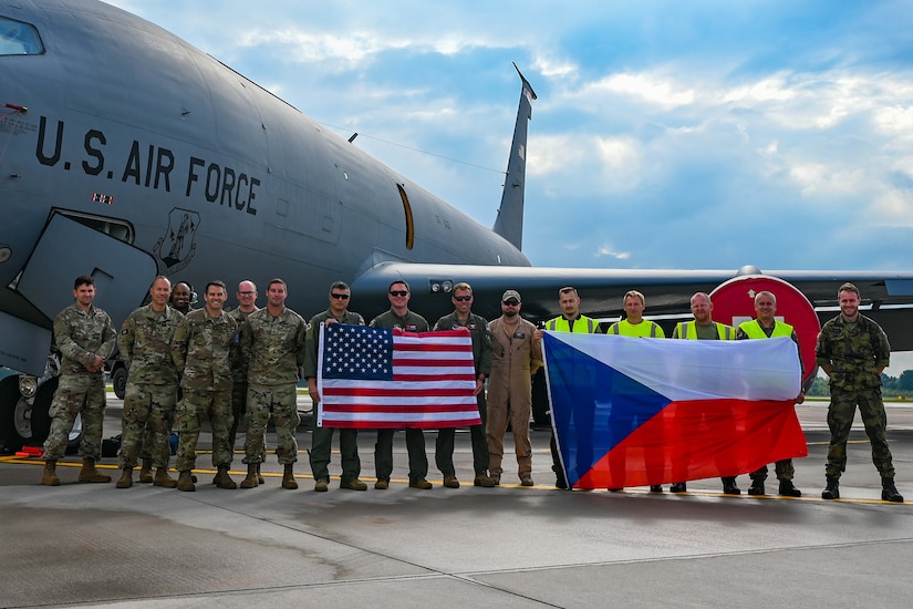 A group of service members hold two flags.