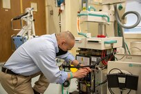 A biomedical equipment technician works on a portable X-ray machine at U.S. Army Medical Materiel Agency’s Medical Maintenance Operations Division at Tracy, California. (U.S. Army photo by Katie Ellis-Warfield/Released)
