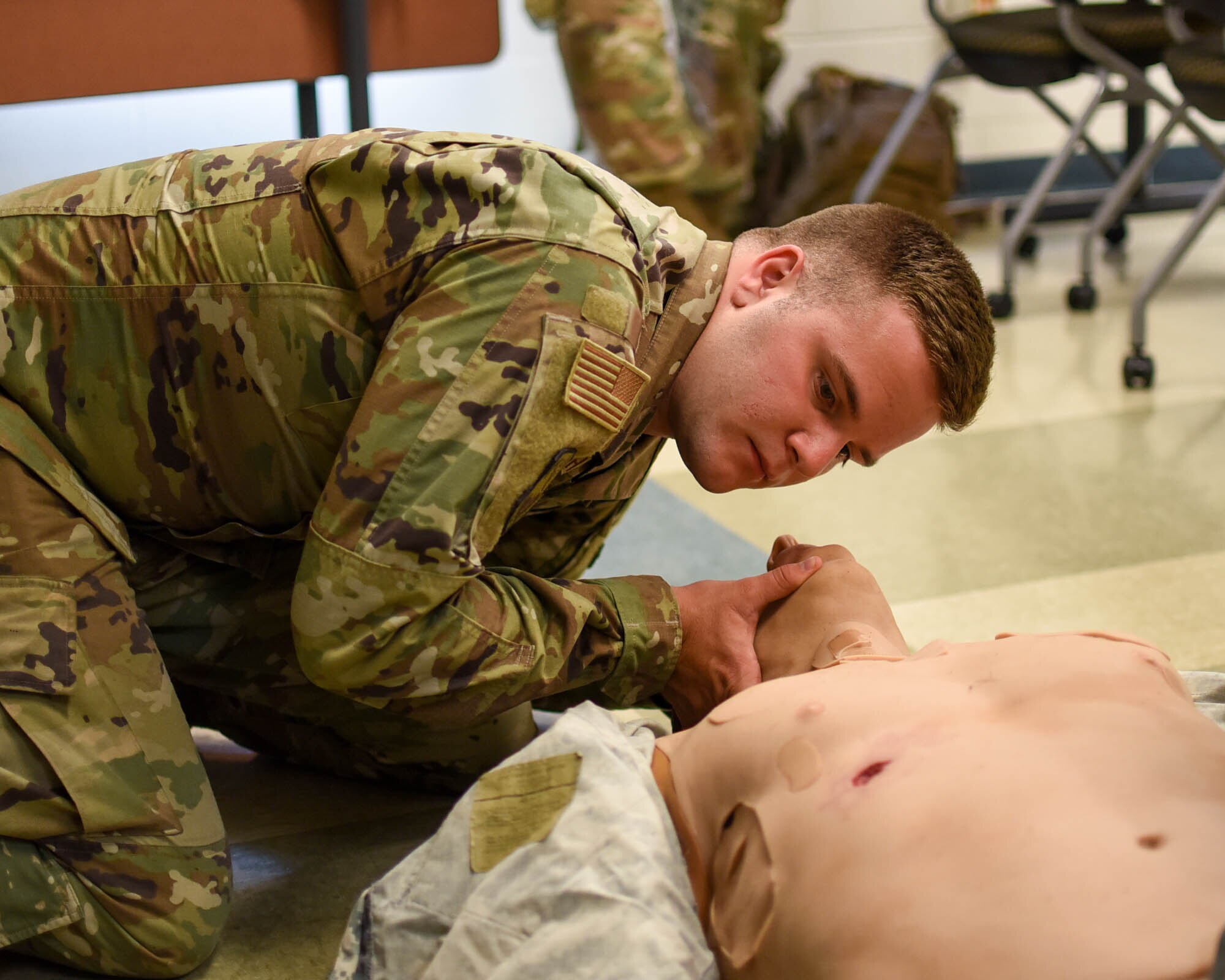 Photo of soldiers and airmen practicing lifesaving techniques on a manikin