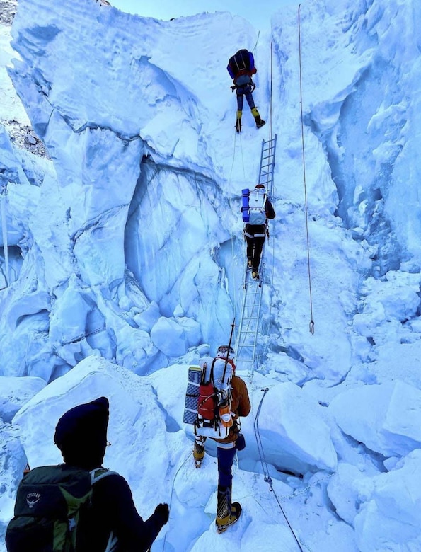 Four men climb a snow-covered mountain.