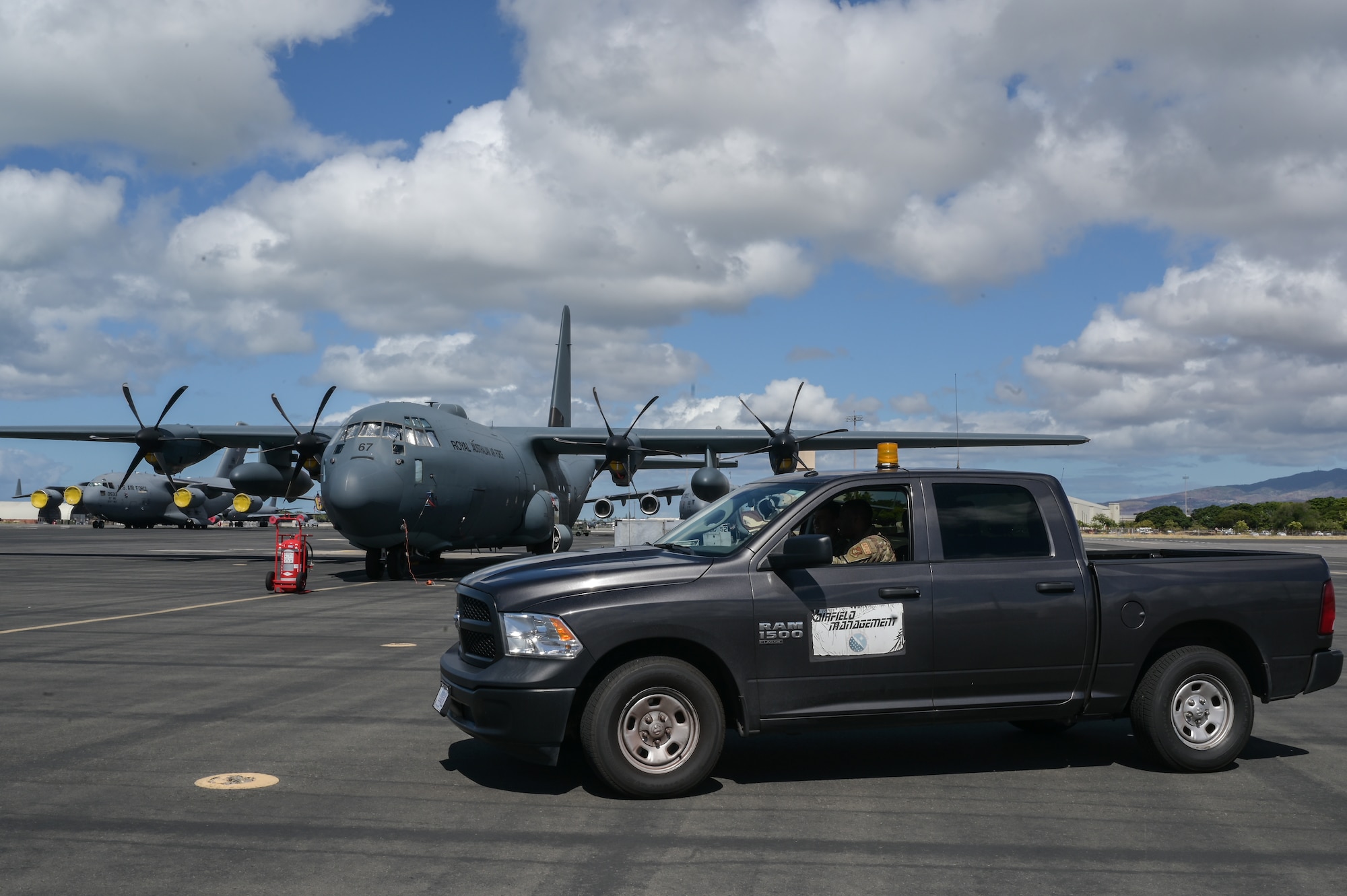 Senior Airman DeMarcus Evans and Airman 1st Class Millan Owens, 15th Operations Support Squadron airfield management journeymen, inspect a parked Royal Australian Air Force C-130 Hercules during Rim of the Pacific Exercise 2022 at Joint Base Pearl Harbor-Hickam, Hawaii, June 25, 2022. The flight’s workload of creating flight and parking plans is increased with the addition of nearly 25,000 additional personnel participating in the exercises. (U.S. Air Force photo by Staff Sgt. Alan Ricker)
