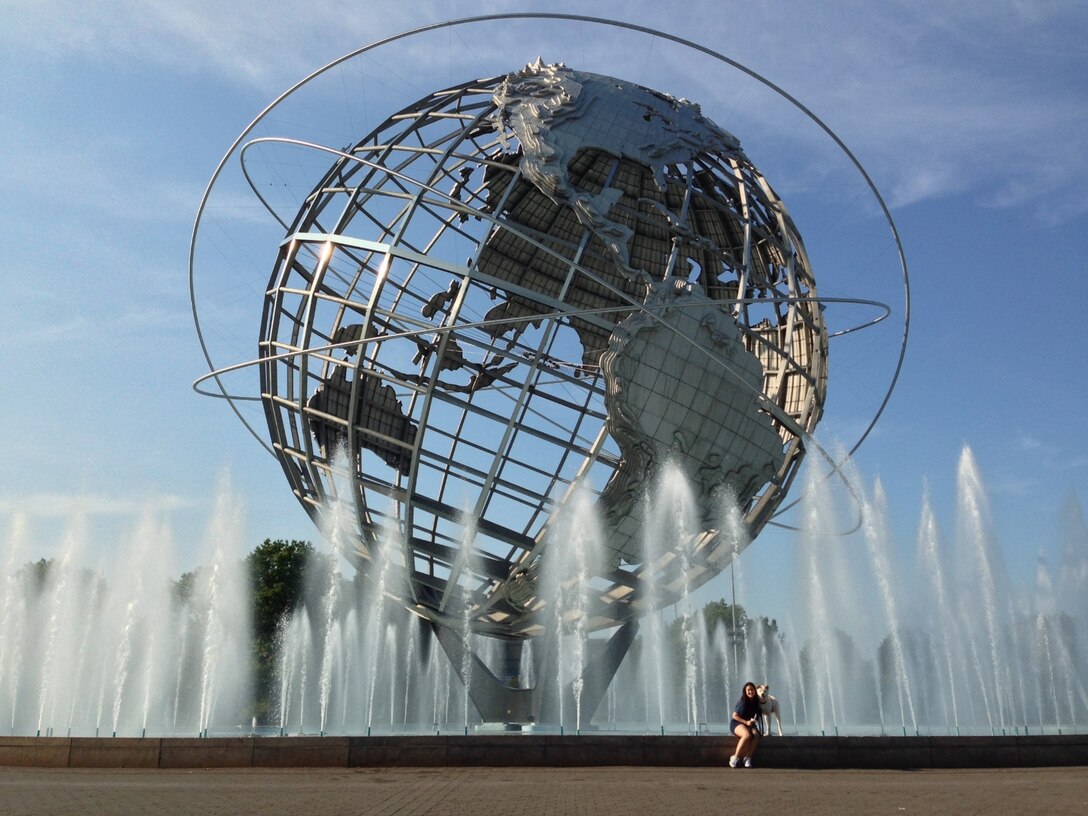 Photo of woman named Mary Hesser with her god Sabot in front of the Unisphere, a steel structure in New York. New York.