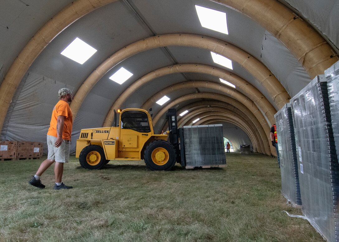 A man and a tractor inside a large, inflatable warehouse.